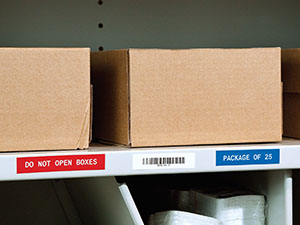 A warehouse shelf with boxes and general identification labels attached for organizational instructions.