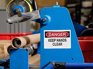 A 'danger keep hands clear' safety label attached to a piece of industrial machinery.
