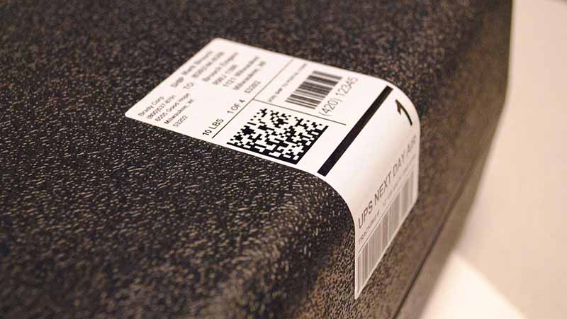 Rubber-based shipping label affixed to a textured package surface.