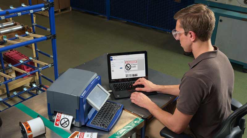 An employee using a Brady S3100 THT benchtop printer to print a no smoking sign.