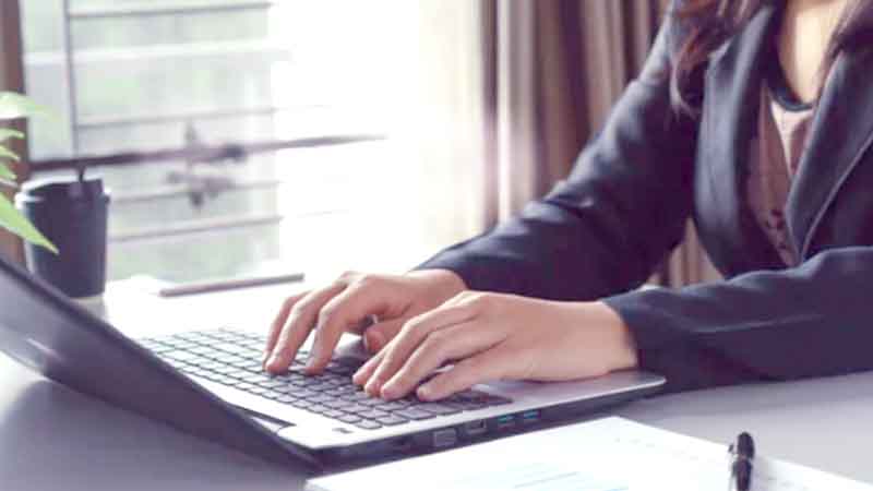 A person in a suit typing on a laptop.